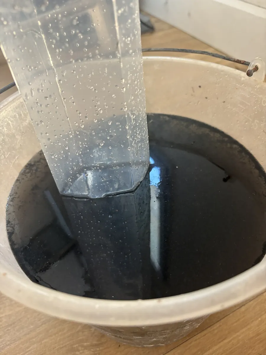 Seau contenant l'eau de rinçage noire issue du nettoyage d'une climatisation