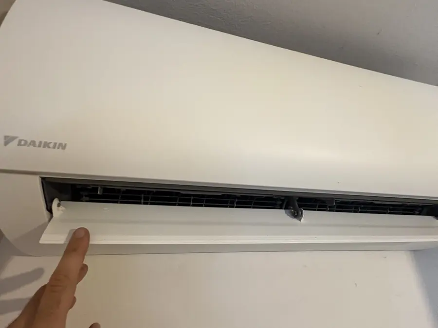 Doigt abaissant délicatement le volet de soufflage du climatiseur